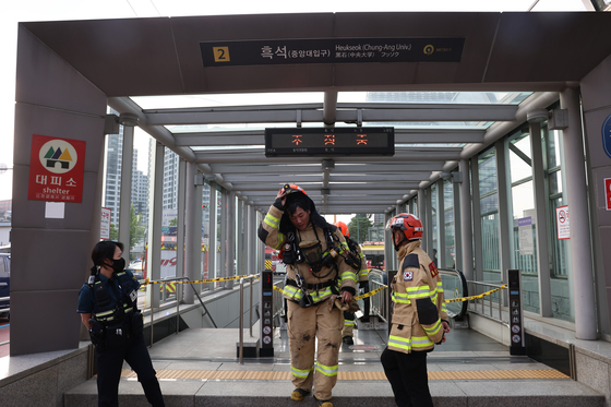Firefighters emerge from an exit of Heukseok Station in Dongjak District, eastern Seoul, on Monday when the subway’s platform was restricted due to smoke. The smoke, the cause of which has yet to be identified, filled the station at around 4:42 p.m. on the same day. Subway line No.9 did not make a stop at the station as a safety measure. [YONHAP]