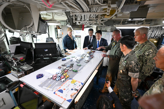 President Yoon Suk Yeol, center, listens to a briefing aboard the American nuclear-powered aircraft carrier USS Theodore Roosevelt(CVN-71), docked at a naval port in Busan on Tuesday. [PRESIDENTIAL OFFICE]