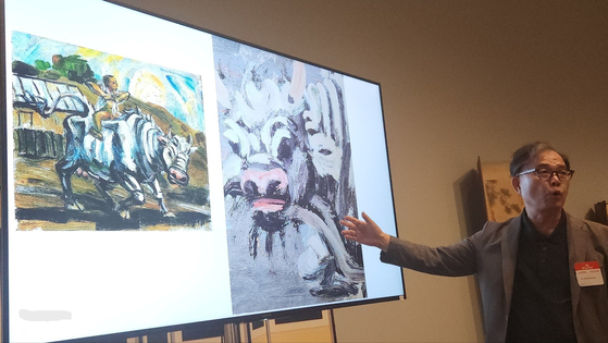 Hong Sun-pyo, a professor emeritus at Ewha University, compares artist Lee Jung-seop's paintings during an appraisal session held at the Los Angeles County Museum of Art on June 26. [JOONGANG ILBO]