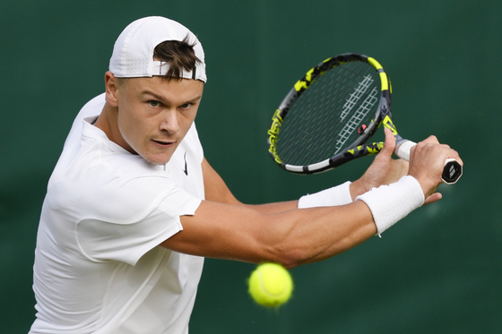 Holger Rune of Denmark plays a backhand return to Kwon Soon-woo of Korea during their first-round match at Wimbledon in London on Tuesday. [AP/YONHAP]