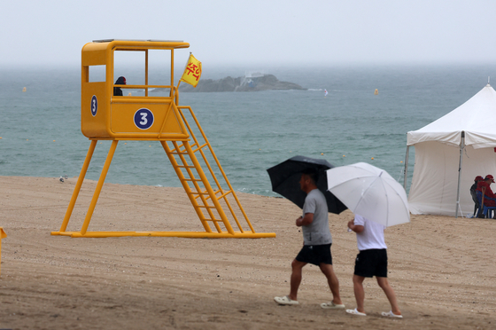 People with umbrellas stroll on Gyeongpo Beach in Gangneung. [YONHAP]