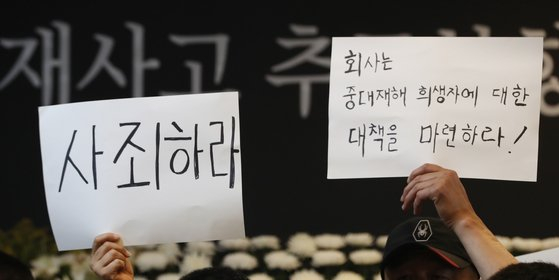 Members of the council for the bereaved families of the deadly fire at Aricell's battery factory plant hold signs demanding an apology at Hwaseong City Hall, where a press conference took place on Sunday. [JOONGANG ILBO]