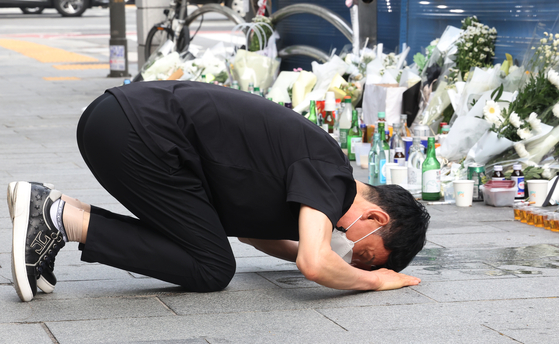 A citizen bows on Thursday in front of flowers and letters left in front of the scene of a fatal car accident that left nine dead near Seoul City Hall on Monday. [YONHAP]