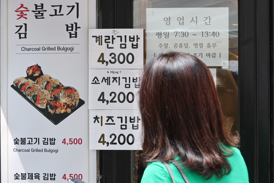 A passerby checks the price of gimbap (seaweed rice rolls) outside a restaurant in Gwancheol-dong in Jongno District, central Seoul on Thursday afternoon. [YONHAP]