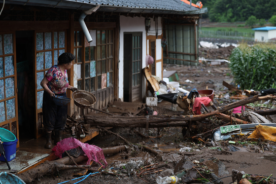 A woman stares at a damaged house partly buried by eroded soil from heavy downpours since Saturday evening in Yeongyang County, North Gyeongsang on Monday. The area received over 142.5 millimeters (5.61 inches) of rainfall on Monday. [YONHAP]