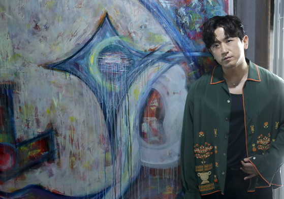 Singer Lee Min-woo of K-pop band Shinhwa poses in front of his work during a press conference at the opening of the exhibition 
