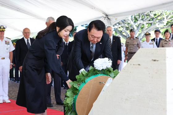 President Yoon Suk Yeol, right, and first lady Kim Keon Hee lay wreaths at the National Memorial Cemetery of the Pacific in Honolulu to respects to fallen veterans of the 1950-53 Korean War on Monday. The presidential couple arrived in Hawaii earlier that day to start a five-day trip to the United States, which later takes to Washington for the NATO summit. [JOINT PRESS CORPS] 