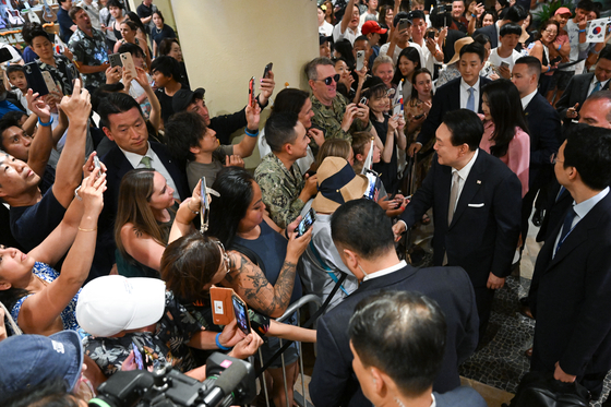 President Yoon Suk Yeol, center right, accompanied by first lady Kim Keon Hee, greets ethnic Koreans and overseas compatriots residing in Hawaii at a hotel in Honolulu on Monday evening. The presidential couple arrived in Hawaii earlier that day to start a five-day trip to the United States which later takes them to Washington for the NATO summit. [JOINT PRESS CORPS] 