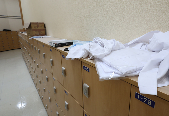 White medical gowns are placed on a cabinet inside a medical school's building in Seoul on Thursday. [YONHAP] 