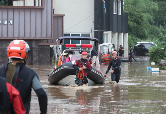 Firefighters evacuate people in Yongchon-dong, Seo District, Daejeon, after overnight rain flooded the area on Wednesday. [NEWS1]