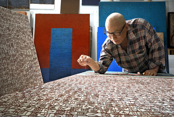 Artist Shin Yong-il works on his artwork featuring texts from “Jikji Simche Yojeol,” which roughly translates to “Anthology of Great Buddhist Priests’ Zen Teachings,” at his studio in Gunpo, Gyeonggi. [PARK SANG-MOON]