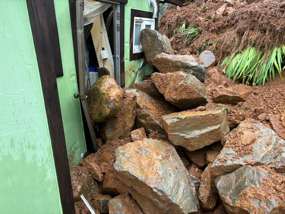 Soil and fallen rocks cover some parts of a house in Geoje on Sunday morning when a heavy rain advisory was in effect. [GYEONGSANGNAM-DO PROVINCIAL FIRE HEADQUARTERS] 