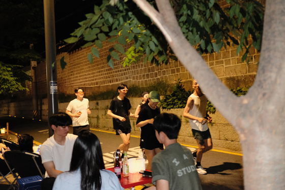 The group runs down the street separating a stretch of trendy restaurants and the stone wall bordering Jongmyo Shrine in central Seoul. [HAN STRIDE]