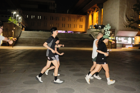 Runners check their watches as they close in on the finish line at Gwanghwamun Square in central Seoul. [HAN STRIDE]