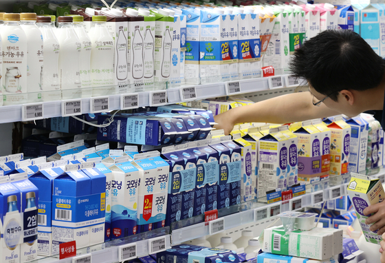 A man pictured above is seen picking out a milk carton pack at a discount mart in downtown Seoul on Sunday. [YONHAP]