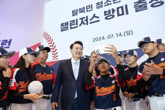 President Yoon Suk Yeol, center, takes a commemorative photo with the Challengers, a baseball team of young North Korean defectors, at a send-off event to the United States at the Blue House in central Seoul on Sunday. [YONHAP]