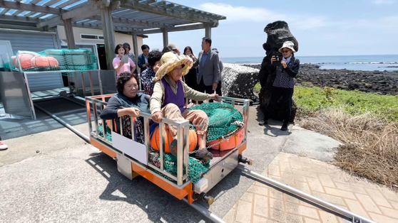 Haenyeo ride a device transporting seafood on a trial run in Ilgwa-ri, Daejeong-eup, Seogwipo City, Jeju Island, on June 13. [JOONGANG ILBO]