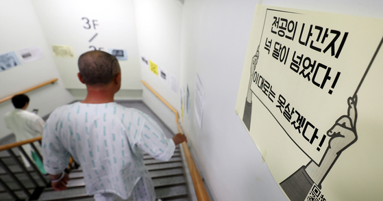 A patient walks beside a poster on the wall, which reads that four months have passed since junior doctors walked out, in a general hospital in Seoul on Monday. [NEWS1] 
