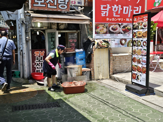An employee at a restaurant serving bosintang, a hot stew featuring boiled dog meat, boils the meat outside the establishment. [JOONGANG ILBO]