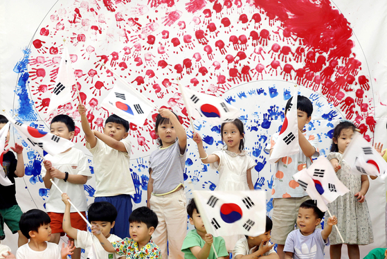 Children wave Korean flags in front of a Korean flag made with their handprints at a day care center in Gwangju on Tuesday, ahead of Constitution Day, which celebrates the establishment of the Korean Constitution on July 17, 1948. [NEWS1]