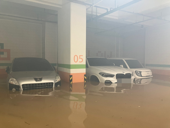 Three cars in a basement parking lot are submerged by muddy water on Tuesday in Wando County, South Jeolla. [JEONNAM FIRE SERVICE HEADQUARTERS]