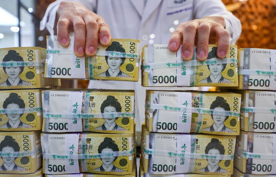 An employee arranges stacks of 50,000 won ($36.28) bank notes at Hana Bank's Counterfeit Notes Response Center in Jung District, central Seoul, on Wednesday. [YONHAP]
