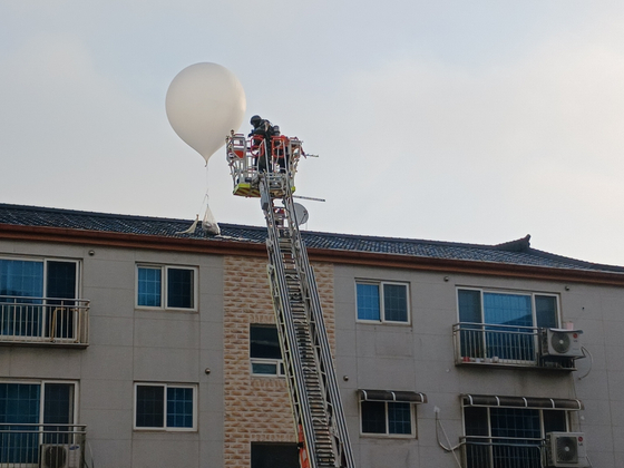 A firefighter clears a waste balloon that fell on the roof of a villa in Hakik-dong, Incheon, on June 9. [NEWS1]