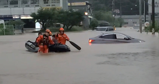 Firefighters rescue individuals who were trapped in a building following a nearby road flooding in Paju on Thursday. [NEWS1] 