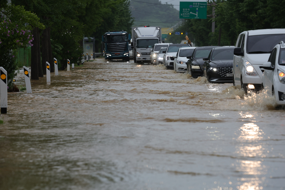 Vehicles move slowly on national route 1 in Munsan-eup, Paju, Gyeonggi, as the road is submerged with water. [YONHAP]