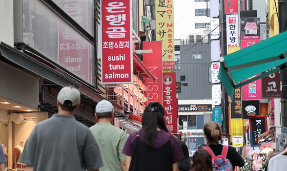 Pedestrians walk by shops in Myeong-dong, central Seoul, in July. [NEWS1]