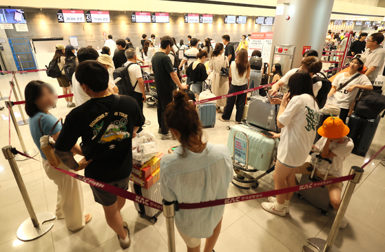 Jeju Air passengers wait to get check in at Incheon International Airport on Friday after a global tech outage led to ticketing issues for budget airlines in Korea. Attendants had to conduct check-ins by hand. [YONHAP] 