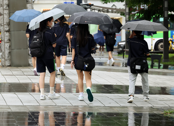 People walk in rain with umbrellas in Gwangju on Friday. [YONHAP] 