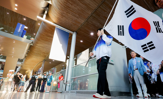 Fencer Gu Bon-gil, center, an Olympic gold medalist, carries the national flag, Taegeukgi, as the South Korean main delegation for the Paris Olympics arrives at Paris Charles de Gaulle Airport in France on Saturday, ahead of the Summer Games. [YONHAP]
