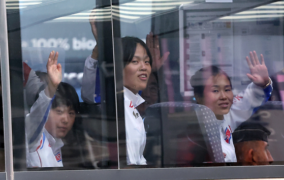 North Korean athletes competing in the 2024 Paris Olympics wave from a bus as they depart from Paris Charles de Gaulle Airport in France on Saturday. [NEWS1]