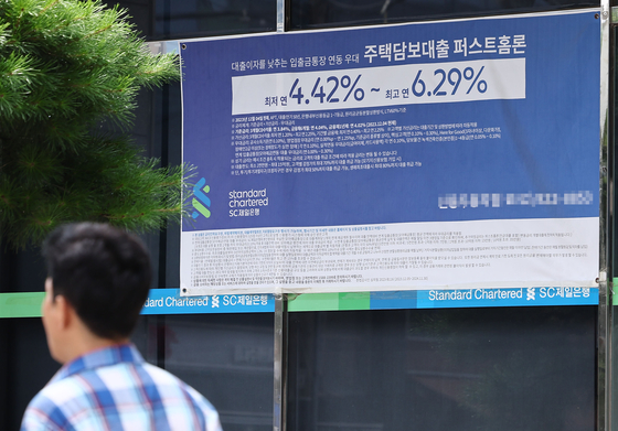 A pedestrian walks past an advertisement promoting mortgage loan products at a bank in Seoul on Sunday.[YONHAP]