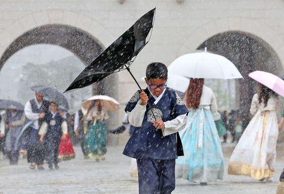 A child visiting Gyeongbok Palace in Jongno District, central Seoul, avoids rain with a flipped umbrella on Monday. [NEWS1]