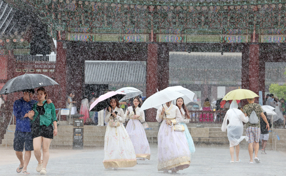 Tourists visiting Gyeongbok Palace in Jongno District, central Seoul, use umbrellas to avoid rain as heavy downpours and strong winds hit on Monday. [NEWS1]