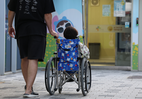 A child in a wheelchair heads toward a pediatrician's office during evening hours in Seoul on June 18. [YONHAP] 
