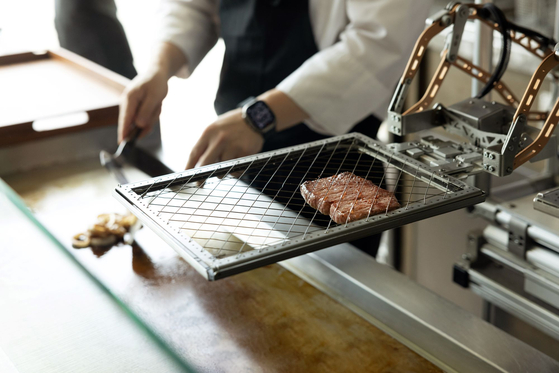 AI robot Andi cooks steak over the grill at Bites & Wine. [ANDAZ SEOUL GANGNAM]