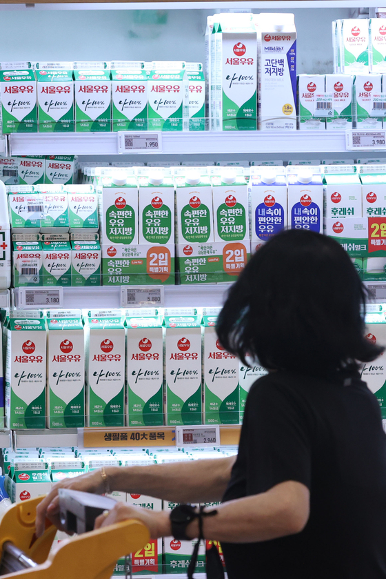 A customer looks at different milk brands displayed at a supermarket in Seoul on Wednesday. [YONHAP]