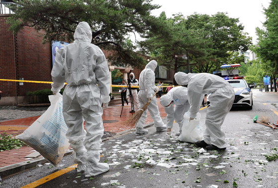 Staffers from local authorities clean the site where North Korea's trash-carrying balloons landed in Jung District, central Seoul, on Wednesday morning. [YONHAP]