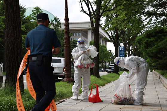 Military officers dispose of a trash-filled balloon that landed in front of the National Assembly Library in Yeouido, western Seoul on Wednesday. [NEWS1]