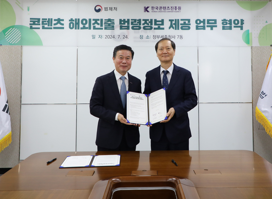 Korea Creative Content Agency (Kocca) President Jo Hyun-rae, left, and Minister of Government Legislation Lee Wan-kyu sign an agreement of cooperation on July 24. [KOREA CREATIVE CONTENT AGENCY]