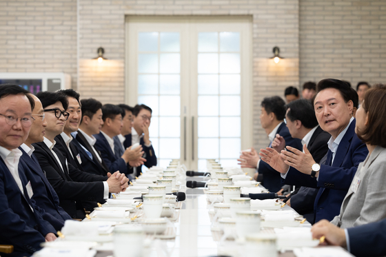President Yoon Suk Yeol, center right, claps during a dinner for the People Power Party’s new leadership at Pine Grass, a garden in front of the Yongsan presidential office in central Seoul, on Wednesday evening. [PRESIDENTIAL OFFICE]