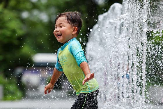 A boy splashes in a fountain in Gwanghwamun Square in Jongno District, central Seoul, on Wednesday, as the midday temperature in the capital reached a high of 31 degrees Celsius (87.8 degrees Fahrenheit). [YONHAP]