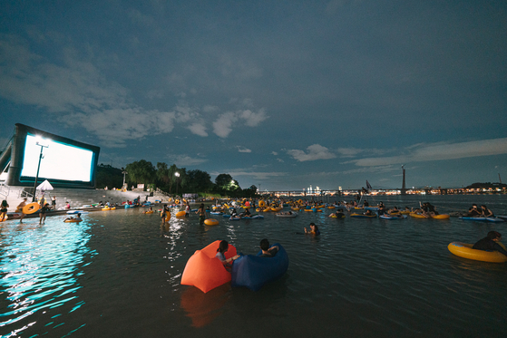People watch a movie while floating on a tube in the Han River in an undated photo provided by the Seoul city government on Thursday. [SEOUL METROPOLITAN GOVERNMENT]