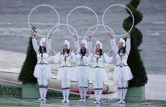Performers hold up hoops in the shape of the Olympic rings on a floating platform along the Seine during the opening ceremony.  [AP/YONHAP]