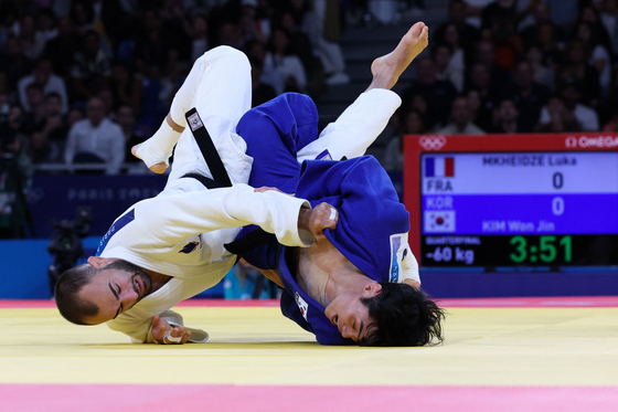 France's Luka Mkheidze and Korea's Kim Won-jin, right, compete in the judo men's -60-kilogram quarterfinal bout at the Champ-de-Mars Arena in Paris on Saturday. [AFP/YONHAP] 
