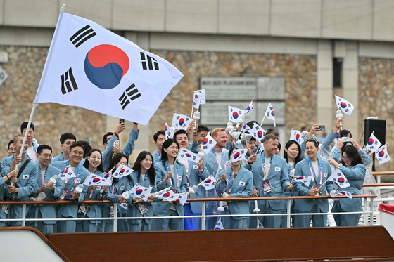 Athletes from Korea wave flags as they sail on a boat along the Seine during the opening ceremony of the Paris Olympics.  [AFP/YONHAP]