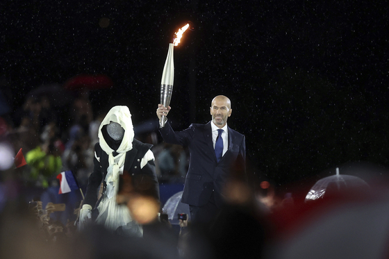 Zinedine Zidane, former French football player and manager, holds the Olympic torch.  [AP/YONHAP]